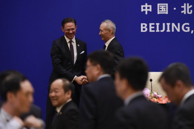 European Commission Vice President Jyrki Katainen (L) shakes hands with China