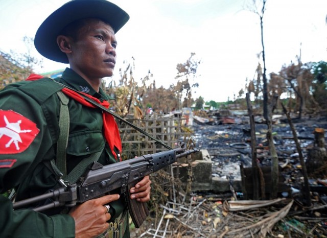A Myanmar soldier stand guard near burnt houses in Ramee township in the western Myanmar Rakhine state on November 1, 2012.
